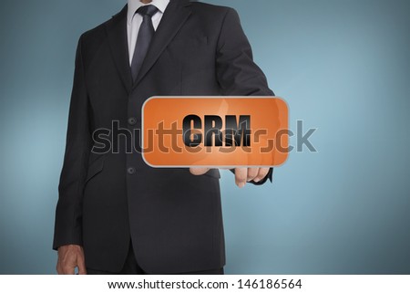 Businessman selecting orange tag with crm written on it on blue background