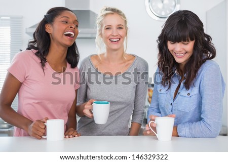 Happy friends having coffee together at home in kitchen