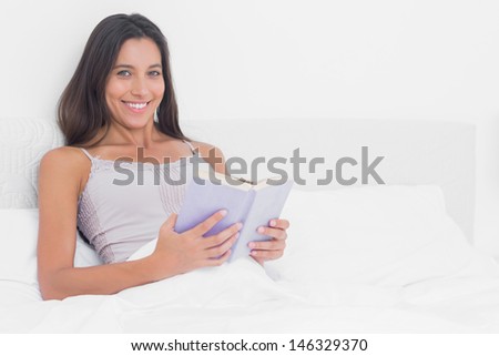 Portrait of a woman reading a book in bed in the bedroom