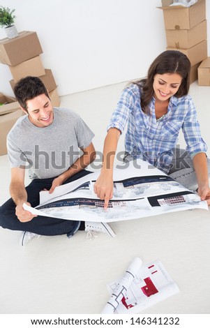 Woman and her husband looking at their house plans sitting in their new house