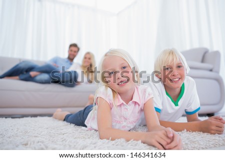 Children lying on the carpet and smiling at camera