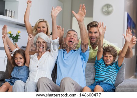 Multi-Generation Family Raising Their Arms Together In The Living Room