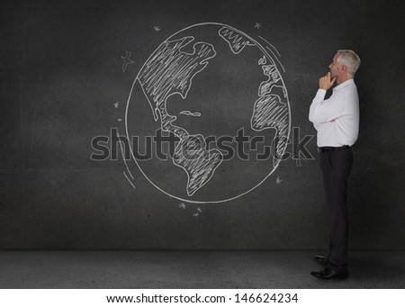 Thoughtful businessman looking at an earth drawn with a chalk on a chalkboard