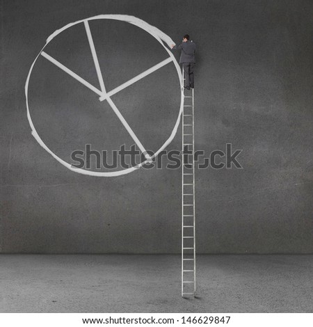 Businessman drawing a giant pie chart on a grey wall