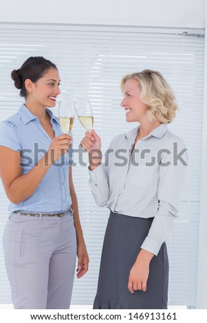 Two colleagues toasting with champagne at the office