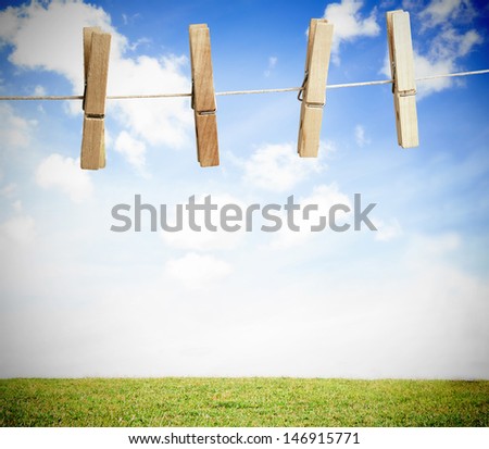 Clothespin on a laundry line outside with bright blue sky with green landscape