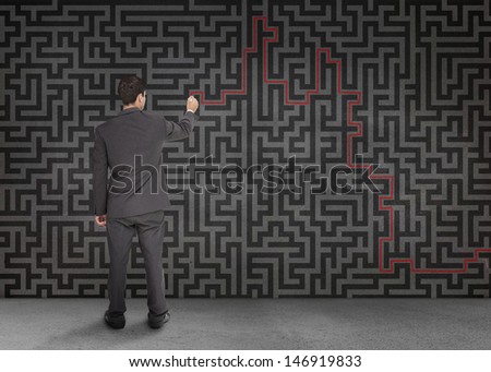 Rear view of a businessman writing a red line through black maze on a wall