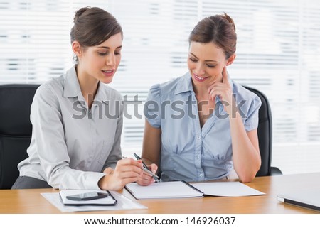 Happy businesswomen working together on documents at desk in office