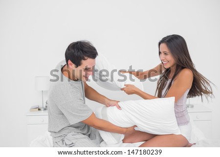 Couple having fun with a pillow fight in bed