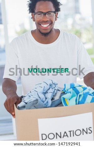 Cheerful man holding donation box full of clothes