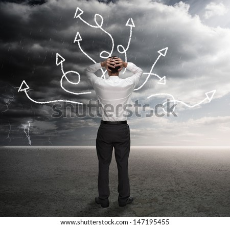 Frustrated businessman looking at a drawing of multiple arrows