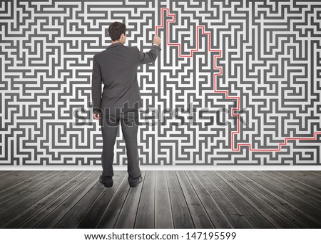 Businessman tracing a red line on a maze drew on the wall