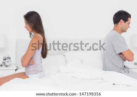 Couple sitting back to back on bed during a conflict