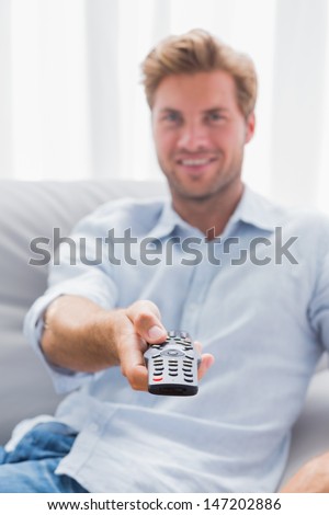 Happy man watching TV in living room and using remote