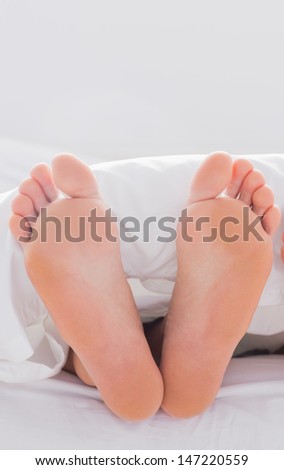 Feet sticking out from the quilt in bed