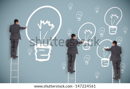 Multiple businessmen on ladders drawing light bulbs on grey wall