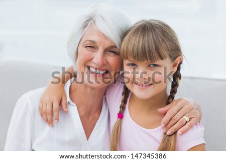 Cute girl and granny sitting on the couch in the living room