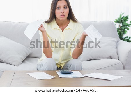 Uneasy woman doing her accounts sat on a couch