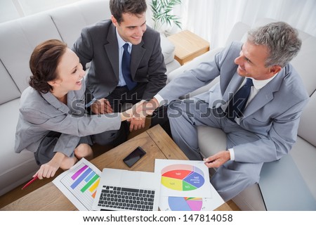 Business People Shaking Hands While Working In Cosy Meeting Room