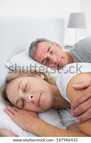 Peaceful Couple Sleeping And Spooning In Bed In Bedroom At Home