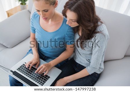 Women surfing the net together and sitting on the sofa