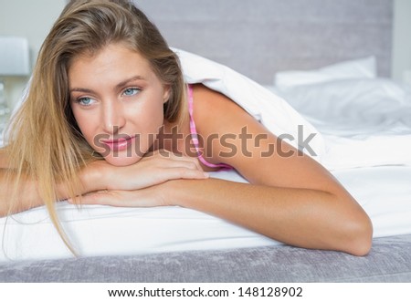 Beautiful blonde lying in her bed thinking in bedroom at home