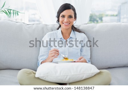 Woman sitting on the couch crossing legs eating fruits in her living room