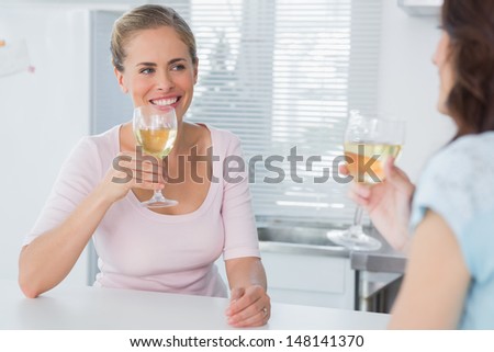 Cheerful women having glass of wine in the kitchen