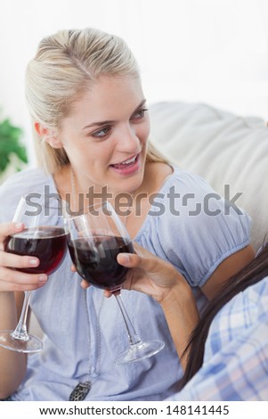 Friends toasting with red wine together at home on the couch
