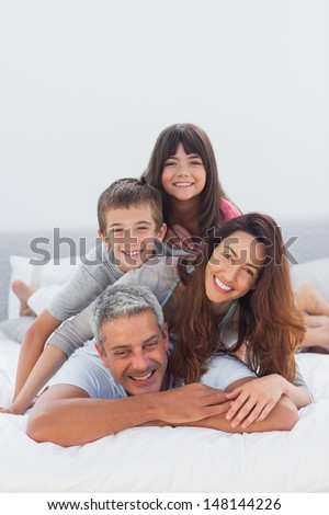 Parents With Their Children Lying On Bed At Home