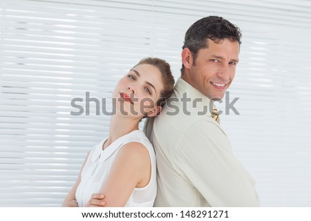 Attractive business team posing back to back in bright office