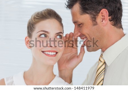 Employee telling secret to his colleague in bright office