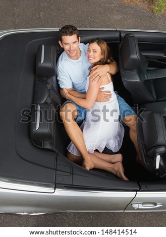 Couple relaxing in the back seat of convertible looking at camera