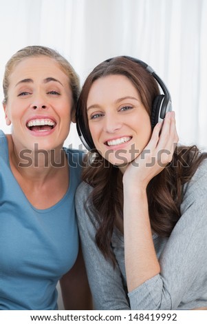 Laughing women listening to music sitting on the sofa
