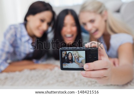 Friends lying on floor and taking a self picture at home in living room
