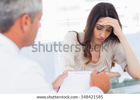 Upset woman listening to her doctor talking about a illness in medical office
