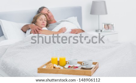 Couple sleeping with breakfast tray on bed at home in bedroom