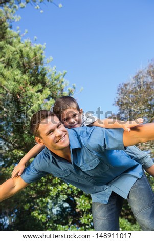Son lying on his fathers back and smiling at camera