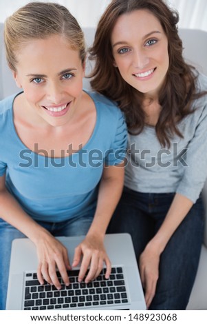 Women posing while surfing the net and sitting on the sofa