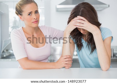 Understanding woman comforting her upset friend laid on the bar