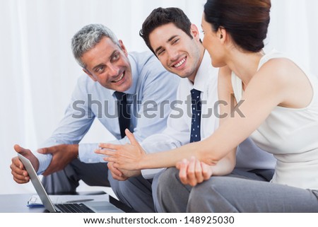 Smiling business people working with their laptop on sofa at office