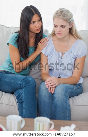 Friend comforting her upset friend at home on the couch