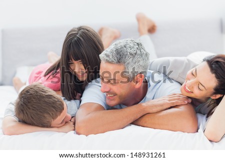 Cute Family Lying On Bed And Talking Together At Home