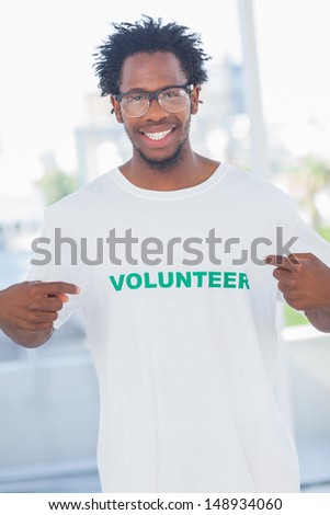 Cheerful man pointing to his volunteer tshirt in a modern office