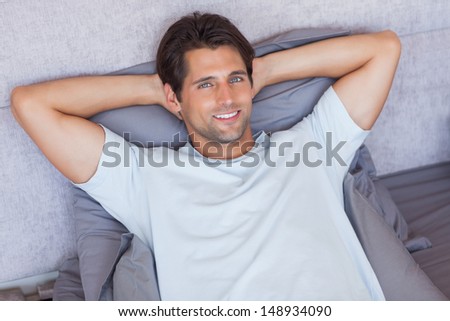 Handsome man lying down in his bed at home