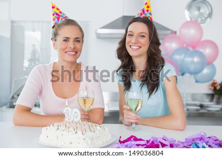 Cheerful women drinking white wine and celebrating birthday and wearing party hats