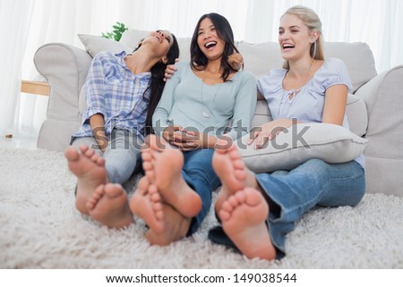 Friends relaxing on floor and laughing at home on couch