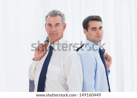 Serious businessmen posing back to back together in bright office