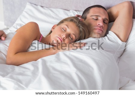 Attractive Couple Sleeping And Cuddling In Bed At Home In Bedroom