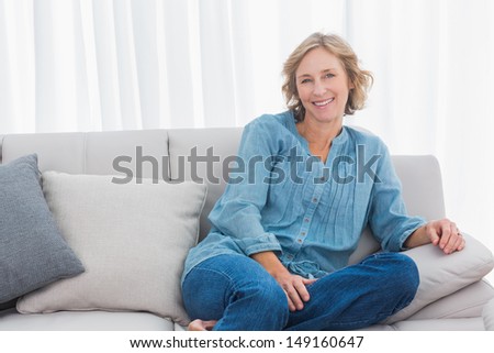 Blonde woman sitting on her couch smiling at camera at home in the sitting room